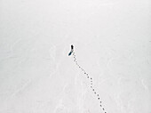 Luftaufnahme einer Person, die auf einer leeren Saline steht, mit Fußspuren, die zu der Person führen, Südaustralien