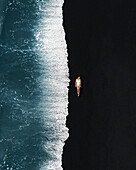 Aerial view of a girl lying on El Golfo black sand beach,Lanzarote,Spain