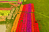 Araihazar,Bangladesh - 22 March 2019: Aerial view of people working in a field placing colourful cloth on the ground for drying in Dhaka,Bangladesh