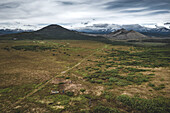 Luftaufnahme eines Geländewagens bei der Überquerung einer wilden Tundra abseits der Straße inmitten von Vulkanen, Kamtschatka, Russland