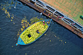Luftaufnahme von ein paar Leuten, die Wassermelonen aus einem kleinen Fischerboot am Buriganga-Fluss in Keraniganj, Dhaka, Bangladesch, abladen