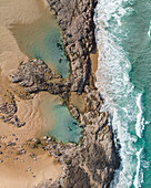 Aerial view of two people floating in separate rock pools at the Champagne Pools,Fraser Island,Australia. Top down perspective