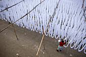 Luftaufnahme von Menschen, die weißen Stoff in Narayanganj, Bangladesch, trocknen