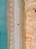 Aerial view of a red car driving on Rainbow beach with the coloured sands rising up from the beach,Queensland,Australia. Top down perspective