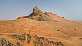Aerial view of a girl on a rocky mountain in the Camel Rock Desert Safari in UAE