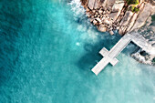 Aerial view of a cross-shaped jetty over blue water with granite rocks and boulders in the image,Port Elliot,South Australia,Australia