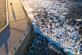 Aerial view of romantic couple walking along seaside walkway at sunset,Cape Town,South Africa
