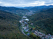 Luftaufnahme eines malerischen, von Bergen und Wäldern umgebenen Tals mit einer charmanten Stadt und einer Straße,Thann,Frankreich