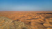Aerial view of a girl on the top of a rocky mountain in the Camel Rock Desert Safari in UAE