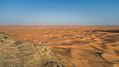 Aerial view of a girl on the top of a rocky mountain in the Camel Rock Desert Safari in UAE
