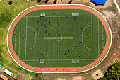 Luftaufnahme eines belebten Fußballfeldes mit Spielern in Aktion und einer Laufbahn, Melton West, Victoria, Australien