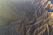 Luftaufnahme eines Canyons zwischen den felsigen und trockenen Bergen in der Wüste im Staat Ajman, Vereinigte Arabische Emirate