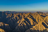 Luftaufnahme eines Canyons zwischen den felsigen und trockenen Bergen in der Wüste im Bundesstaat Ajman, Vereinigte Arabische Emirate
