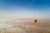 Aerial view of hot-air-balloon flying in the clouds of the Murqquab desert in Dubai,U.A.E