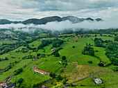 Luftaufnahme einer üppig grünen Landschaft mit sanften Hügeln und einem abgelegenen Dorf, Infiesto, Asturien, Spanien
