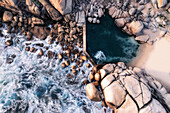 Aerial view of a tidal rock pool,taken with a long exposure shutter setting,showing the waves crashing onto the rocks and flowing into the pool,Cape Town,Western Cape,South Africa