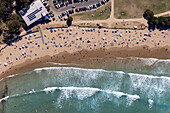 Aerial view of a crowded sandy beach with sunbathers and colorful umbrellas beside the ocean waves,Lorne,Australia