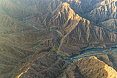 Luftaufnahme eines Canyons zwischen den felsigen und trockenen Bergen in der Wüste im Bundesstaat Ajman, Vereinigte Arabische Emirate
