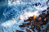 Aerial view of a boulder in the ocean with large waves crashing around it,using a long exposure to capture the motion of the waves,Cape Town,Western Cape,South Africa