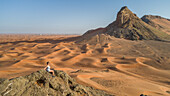 Aerial view of a girl on the top of a rocky mountain in the Camel Rock Desert Safari in UAE