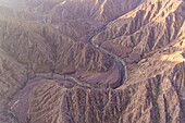 Luftaufnahme eines Canyons zwischen felsigen und trockenen Bergen in der Wüste im Staat Ajman, Vereinigte Arabische Emirate