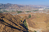 Luftaufnahme eines Canyons zwischen den felsigen und trockenen Bergen in der Wüste im Staat Ajman, Vereinigte Arabische Emirate