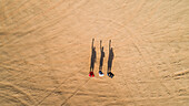 Aerial view of friends waving with their shadows in the Sharjah desert,U.A.E