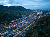 Luftaufnahme einer malerischen Stadt umgeben von ruhigen Bergen und üppigem Grün bei Sonnenuntergang, Thann, Frankreich