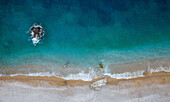 Aerial view of a couple of guys swimming in crystal clear water illuminated by sunlight close to an empty beach,Cala Moraig,Zona Encinas,Cumbre del Sol,Alicante,Spain