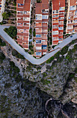 Aerial view of a lively townscape with organized architecture divided from a cliff by an asphalt road,Zona Encinas,Cumbre del Sol,Alicante,Spain