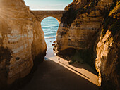 Aerial view of cliffs,ocean,bridge,arch,and person at Pinhao fort bridge,Lagos,Portugal