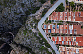 Aerial view of a lively townscape with organized architecture divided from a cliff by an asphalt road,Zona Encinas,Cumbre del Sol,Alicante,Spain
