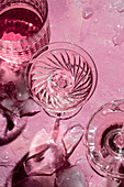 Crystal glasses and ice cubes on a pink background