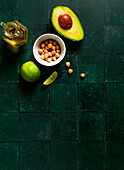 Avocado, chickpeas, olive oil and lime on a dark green background