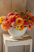 Dahlienarrangement in weißer Vase auf Holzhocker