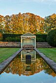 Teich mit Pavillion und Buchsbaumhecken im Herbstgarten