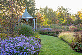 Graspfad führt zu Pavillon mit Gräsern und Astern im spätsommerlichen Garten
