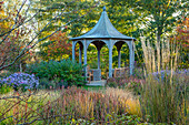 Graspfad zu Pavillon mit Herbst-Blaugras (Sesleria autumnalis) und Sommer-Astern (Aster x frikartii 'Mönch') im Spätsommergarten