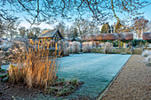 Verschneiter Wintergarten mit Gräsern und Laubengang aus Hainbuchen