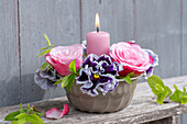 Rose und Primeln in Backform mit Kerze