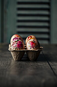 Easter eggs with floral patterns in an egg carton