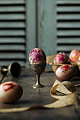 Easter egg with floral painting in a rustic egg cup