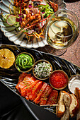 Salmon sashimi with side dishes, salad and white wine