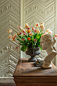 Tulpen (Tulipa) im Metallgefäß auf Holztisch vor gemusterter Wand
