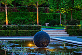 Beleuchtete schwarze Kugel-Skulptur im modernen Garten-Teich