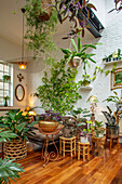 Wohnzimmer mit grünen Zimmerpflanzen, weißer Backsteinwand und Holzfußboden