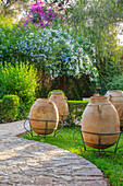 Terrakottagefäße und blühende Bougainvillea auf Gartenweg in Marokko