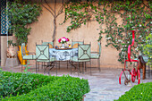 Terrasse in Taroudant mit schmiedeeisernen Gartenmöbeln und blühender Kletterpflanze