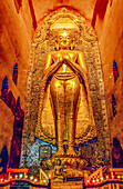 Ananda Temple, Bagan, Myanmar. Wide angle vertical portrait of large gold Ananda Buddha statue in the shrine built during 12th century.