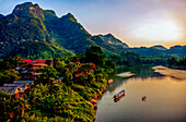 Mekong River village, Laos. Landscape view of mountain village at sunset lighting river and mountains.